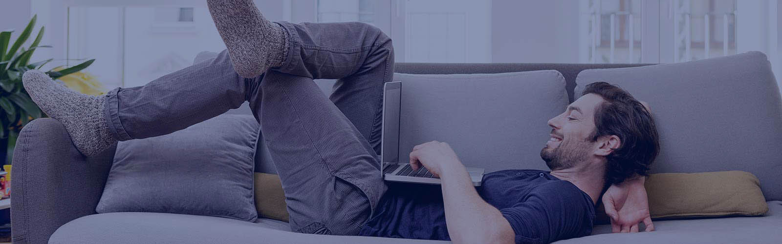 Relaxed man lying on couch using laptop