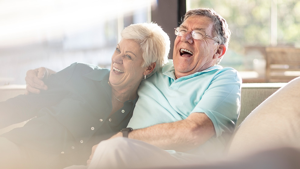 Mature couple laughing on the couch together