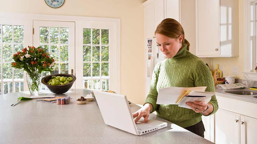 woman in kitchen reviewing her financial statements