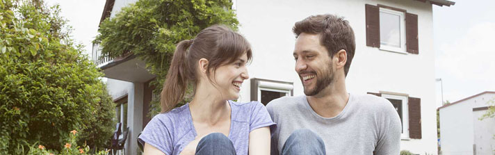 Couple is sitting in front of their new home