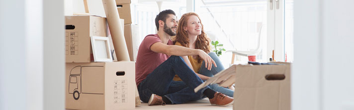 Young couple sitting in new home with boxes