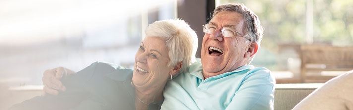 Mature couple laughing on the couch together