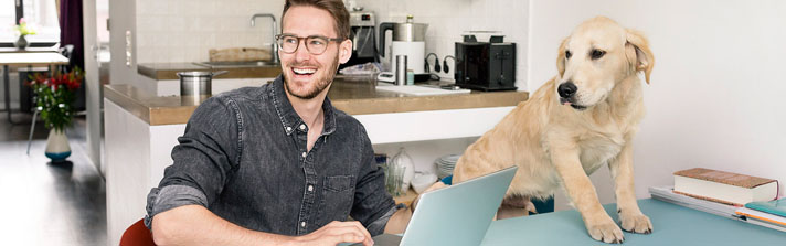 Man looking at the laptop with the dog