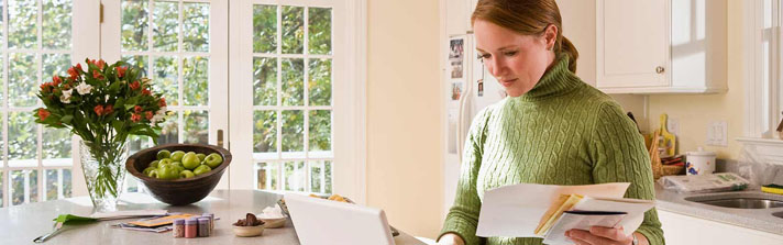 woman in kitchen reviewing her financial statements