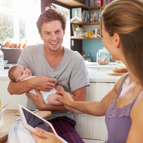 Young couple with their baby having breakfast at the kitchen table