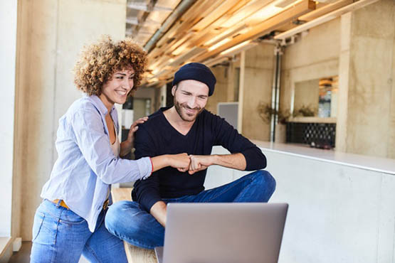 Couple celebrating news while looking at laptop